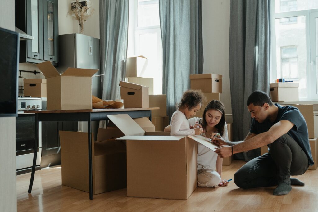 benefits of homeownership: A family is sitting on the floor and boxes are places around them