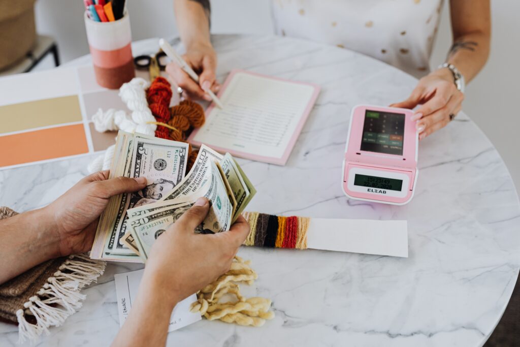 Closing Costs: Two people sitting on the table, one is counting money the other one is holding the calculator and writes on a notebook